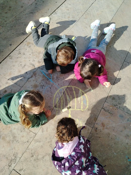 Niños y niñas realizando una actividad creativa con tizas al aire libre en La Xarranca, espacio lúdico en Tordera